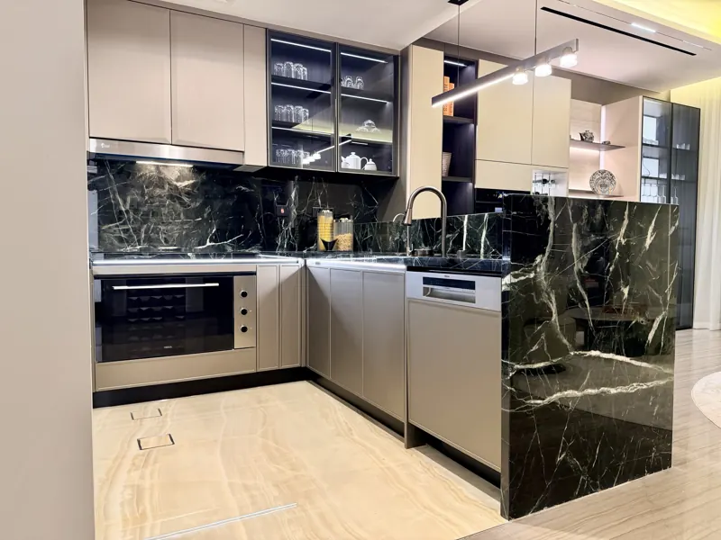 Handleless kitchen with green marble backsplash and integrated appliances, real photo